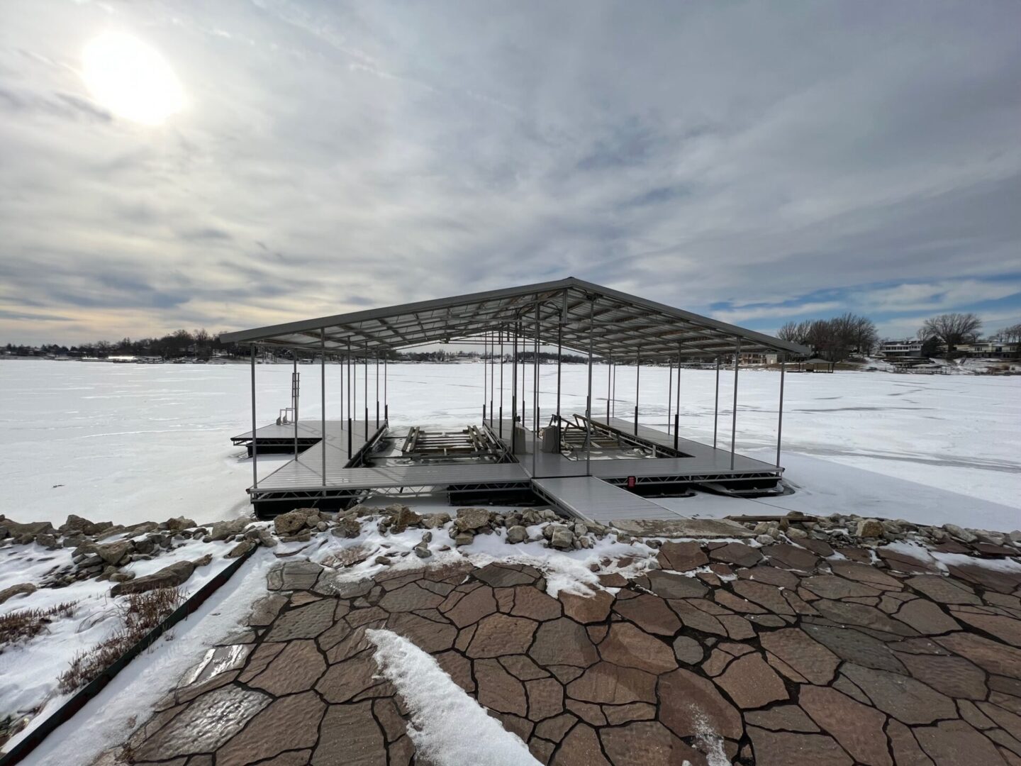 A dock with snow on the ground and sun shining