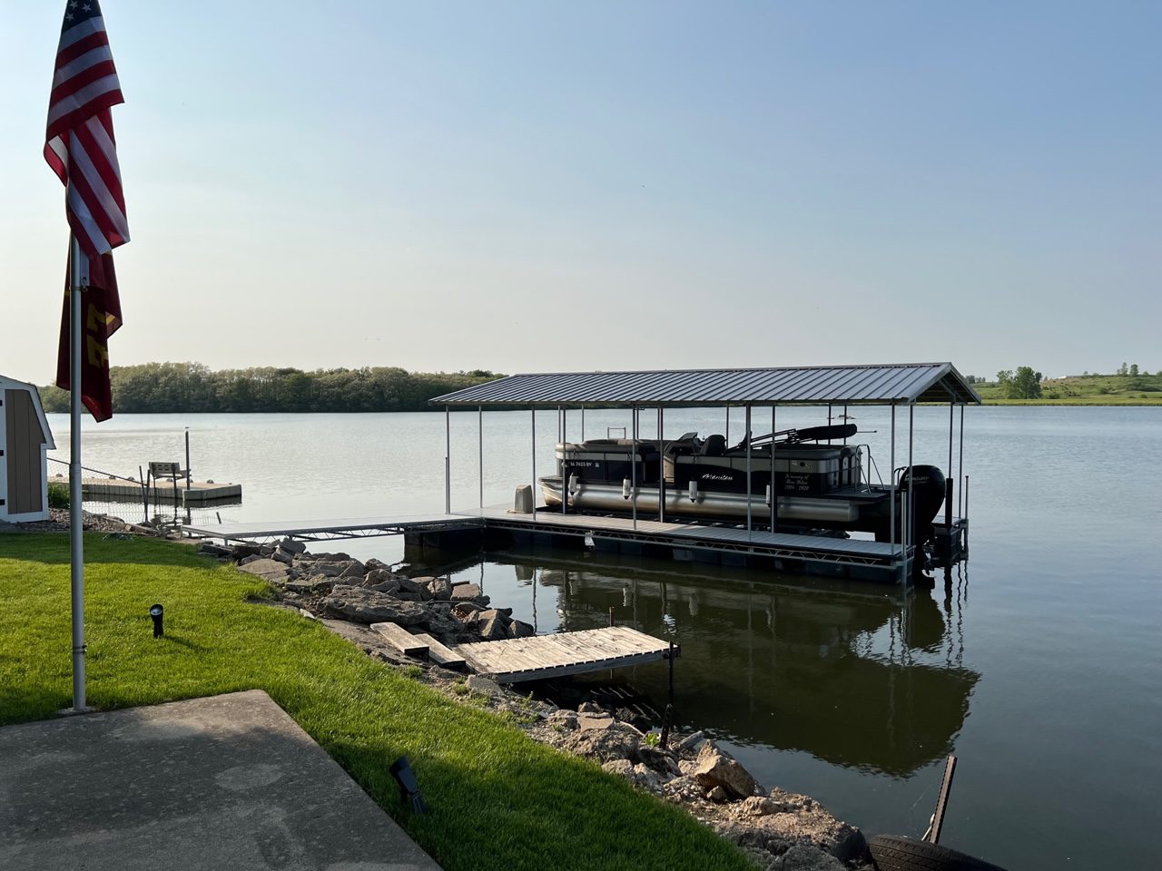 A dock with a boat in it and grass around.