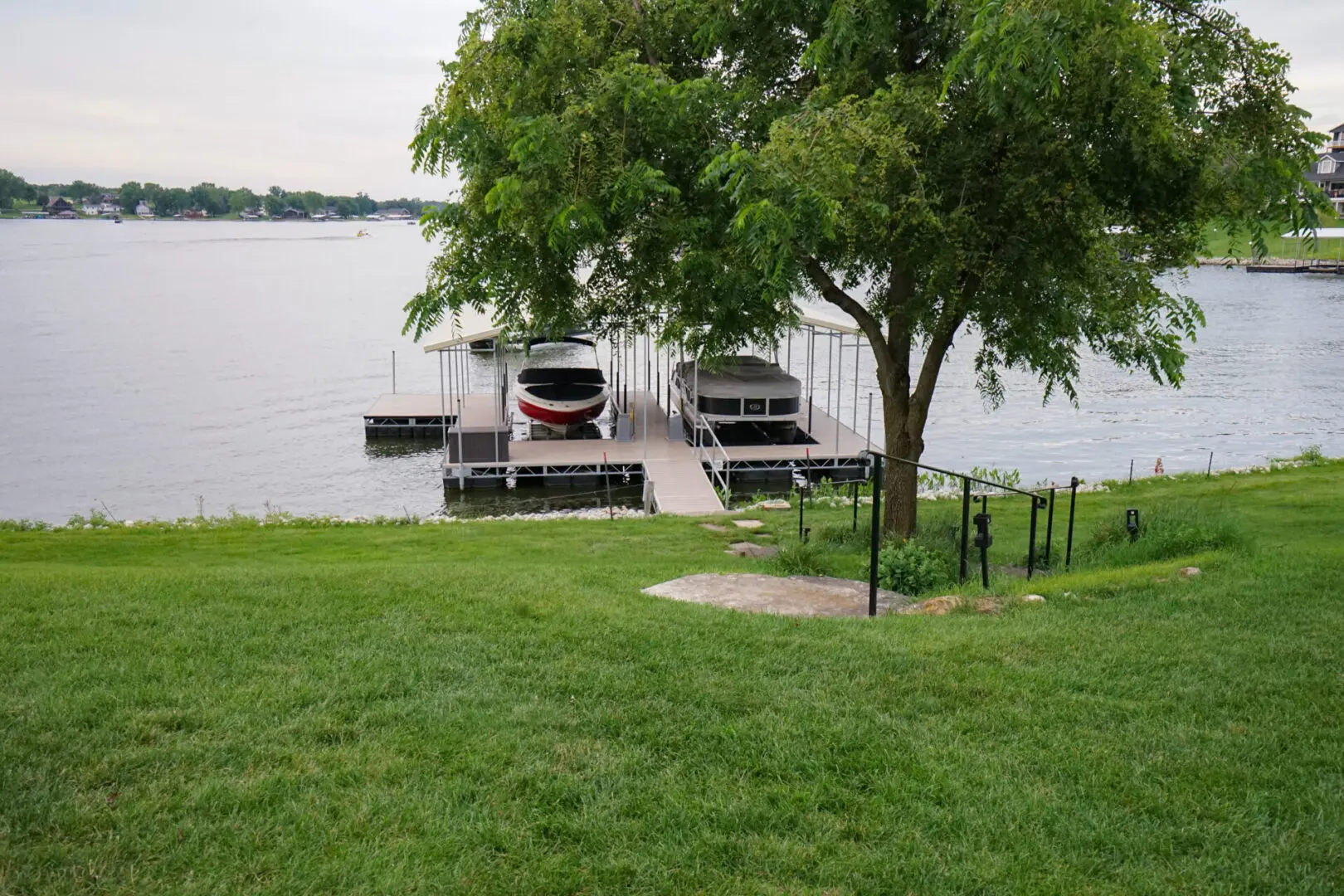 Lakefront dock with two boats under cover.