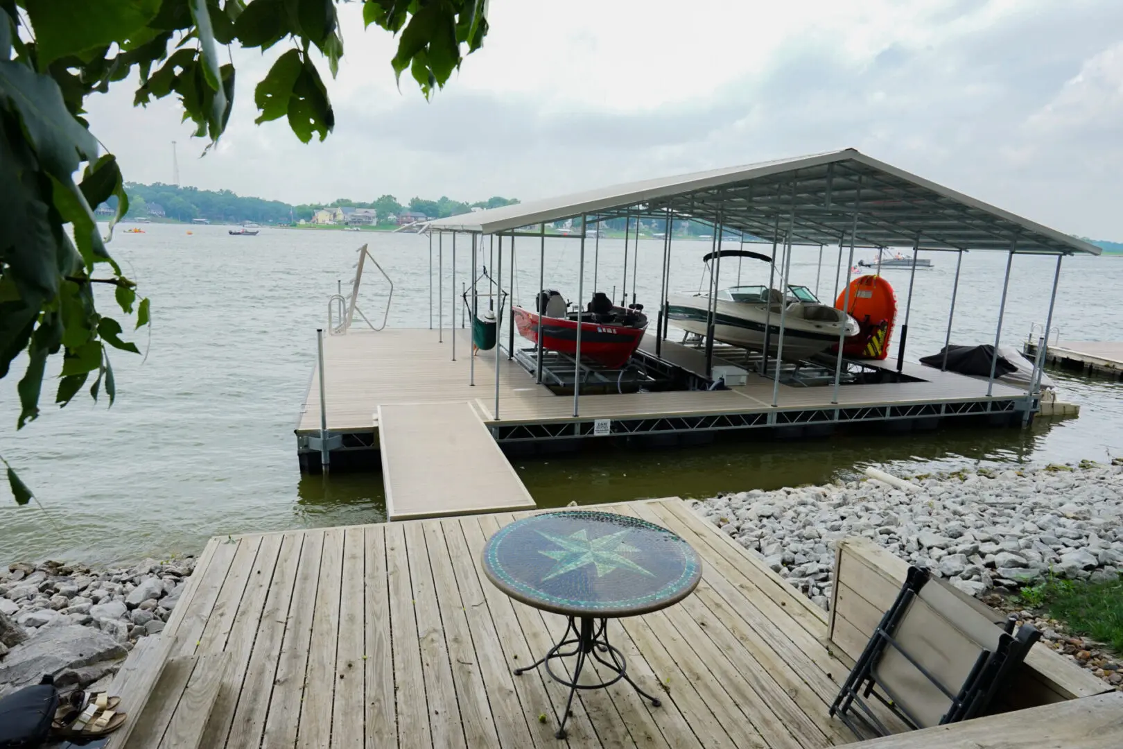 Here's an alt tag for the image: Lakefront dock with boats and patio table.