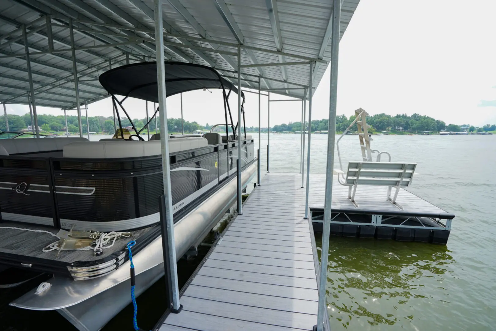 Pontoon boat docked under covered slip.